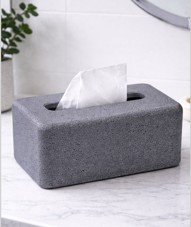 Gray concrete-style tissue box holder with tissues on a marble surface.