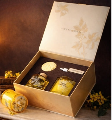 Gifting set with bottles and a box on a decorative table with candles and flowers.