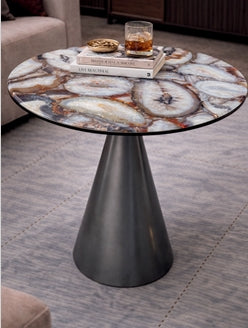 Modern side table with a glass top and metallic base in a living room setting.