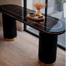 Modern black dining table with gold accents in a room with large windows.