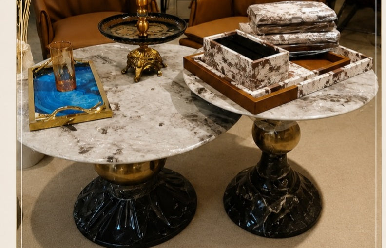 Decorative table with marble surface and gold accents in a room with framed pictures on the wall.