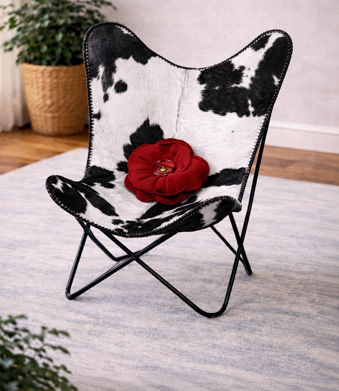 Butterfly chair with black and white cowhide pattern and a red flower on a light gray rug.