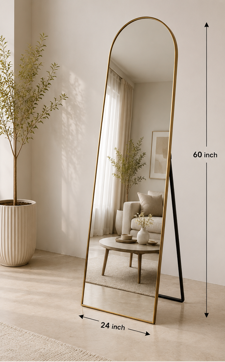 An arched full-length floor mirror with a slim gold metal frame and black stand legs, shown in a styled interior room. The image includes text overlays with dimensions (60 inch by 24 inch), product features, and available finishes labeled Gold, Black, and Brass.