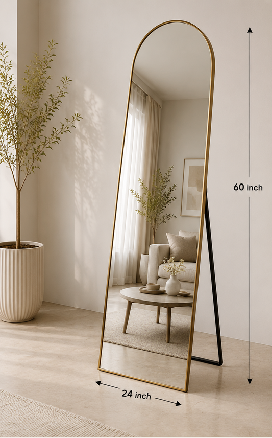 An arched full-length floor mirror with a slim gold metal frame and black stand legs, shown in a styled interior room. The image includes text overlays with dimensions (60 inch by 24 inch), product features, and available finishes labeled Gold, Black, and Brass.