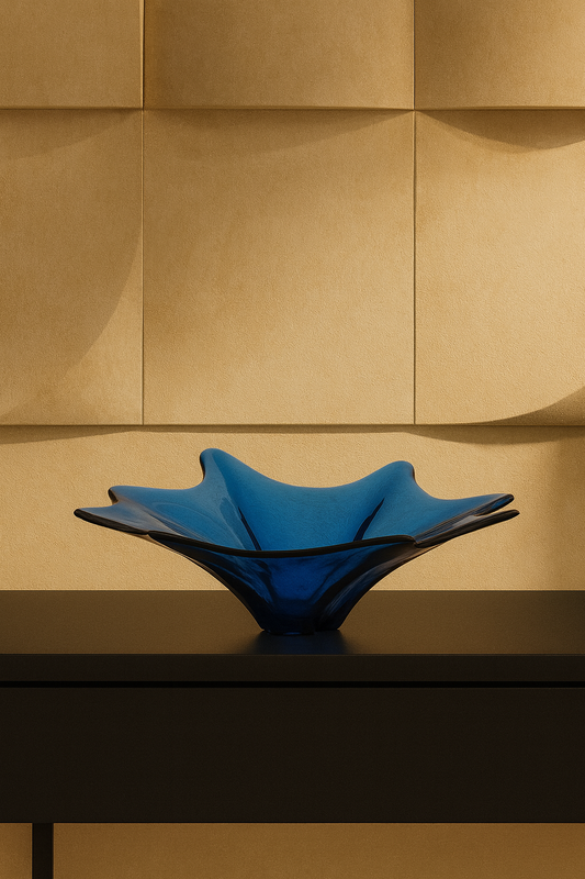 Blue glass bowl on a reflective surface with a gold paneled wall background