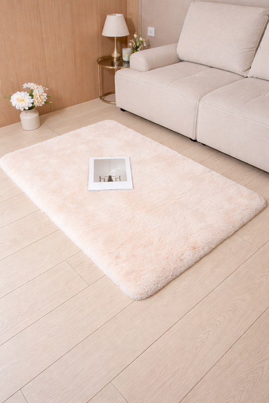 Beige rug on a wooden floor with a sofa and side table in the background