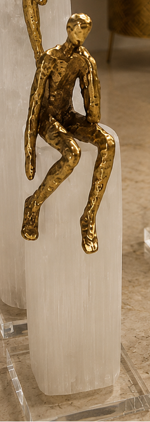Gold sculptures of people on clear stands in a room with decor elements.