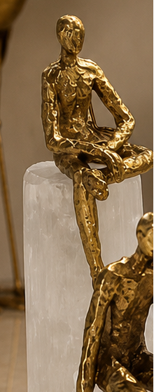 Gold sculptures of people on clear stands in a room with decor elements.