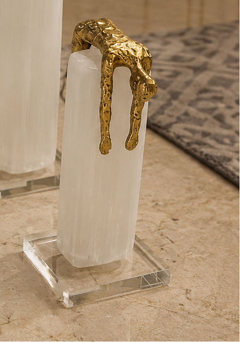 Gold sculptures of people on clear stands in a room with decor elements.
