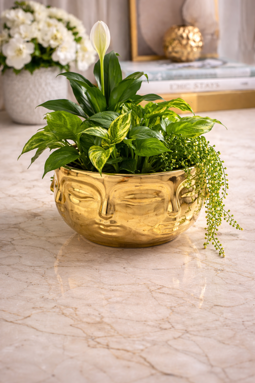 Gold face-shaped planter with green plants on a marble surface