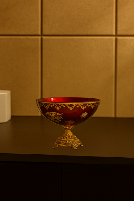 Decorative red bowl with gold detailing on a dark surface against a gold tiled wall.