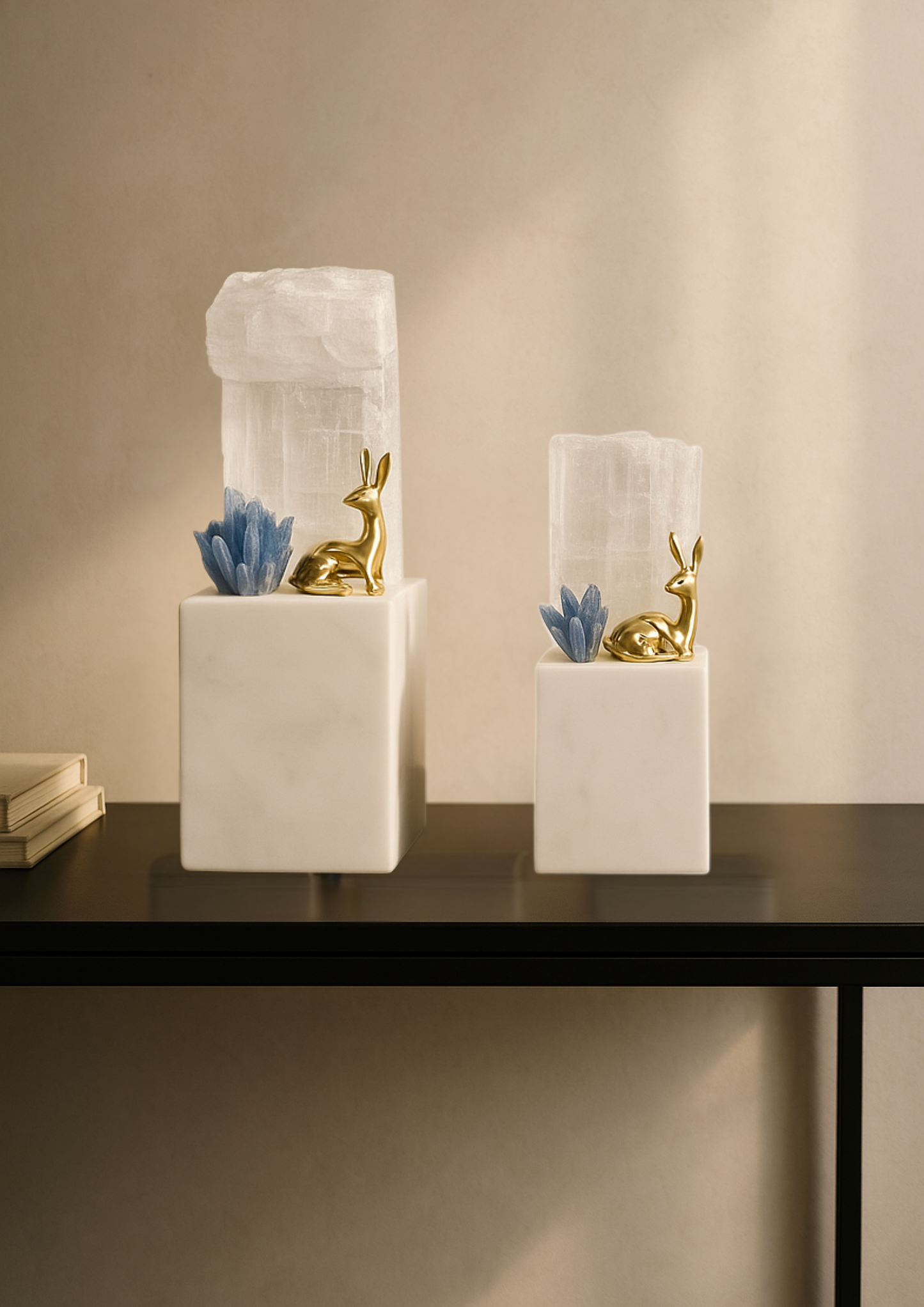 Two decorative items with gold deer figurines and blue flowers in white vases on a table.