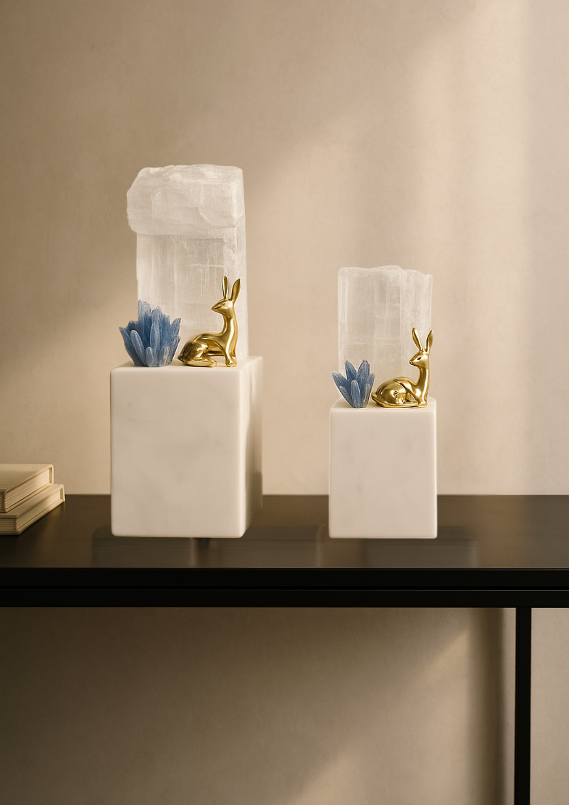 Two decorative items with gold deer figurines and blue flowers in white vases on a table.