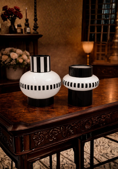 Two black and white striped vases on a wooden table with a warm background.