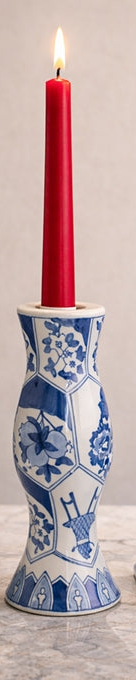 Two blue and white ceramic candle holders with red candles on a marble surface.