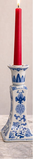 Two blue and white ceramic candle holders with red candles on a wooden surface.