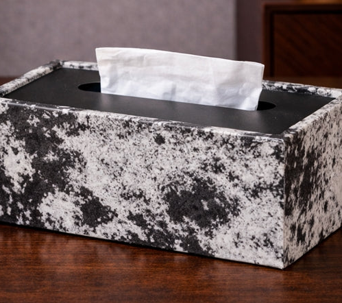 Decorative tissue box with marble-patterned cover on a wooden surface