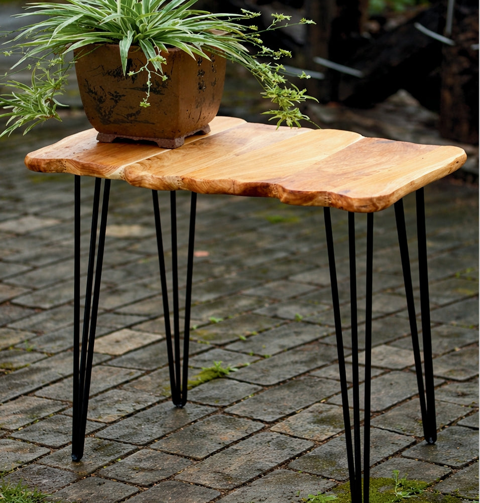 Wooden side table with black hairpin legs on a stone patio
