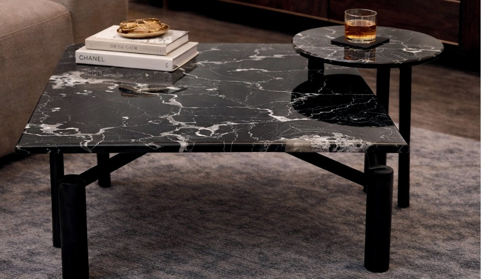Marble coffee table with a glass of whiskey and books in a living room setting.