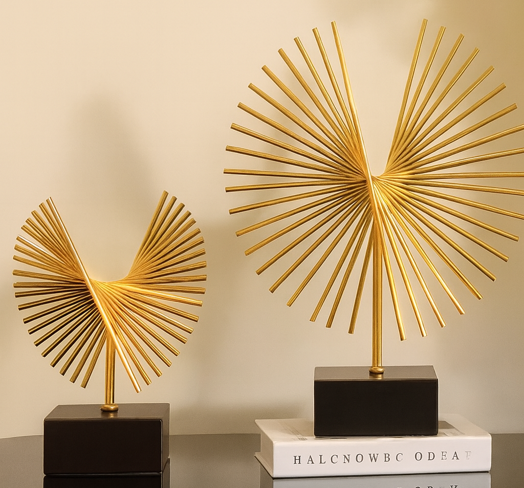 Two gold decorative sculptures on a black surface with a beige wall background