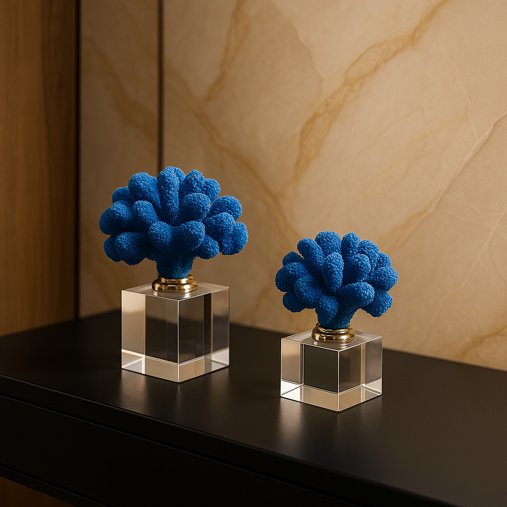 Two blue coral-like sculptures on clear square bases against a marble wall.