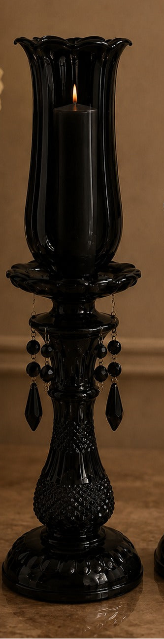 Two black candle holders with candles on a beige surface.