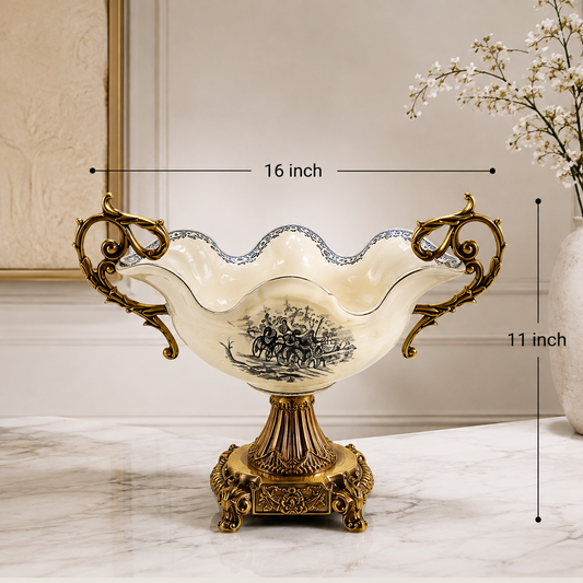 An ornate pedestal bowl with decorative gold-tone handles and base, shown on a marble surface with overlaid dimension lines reading 16 inch wide and 11 inch tall. A material/finish/color legend appears along the bottom, and a vase of small white flowers sits in the background.