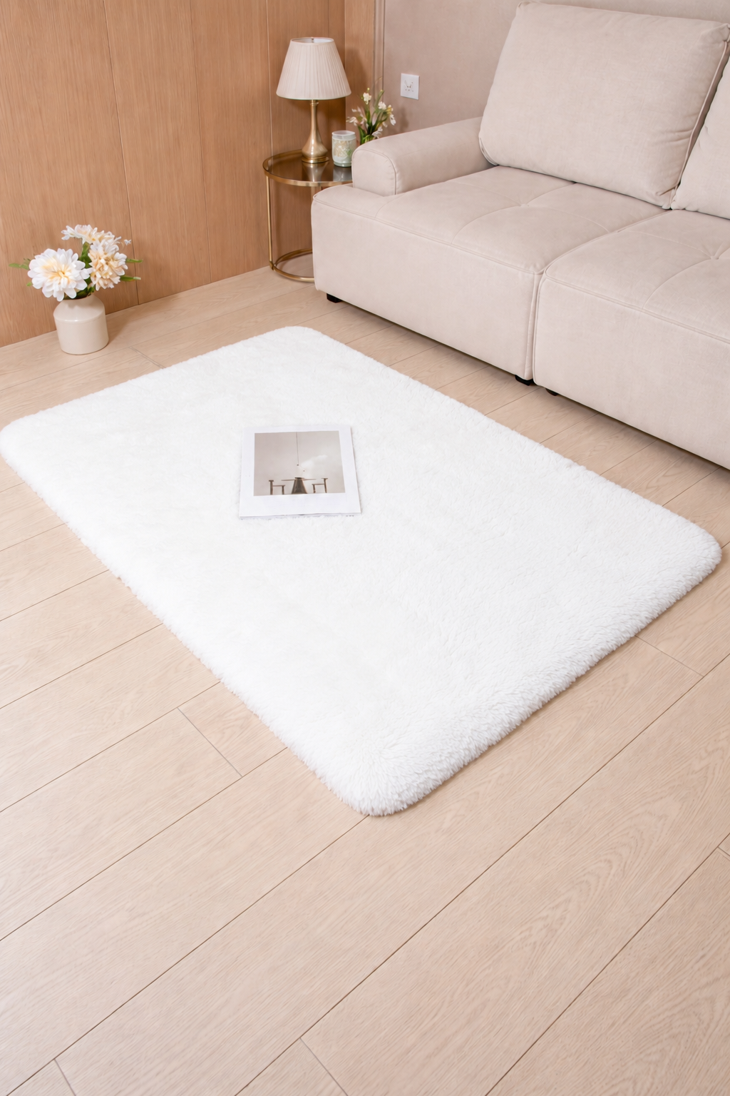 White rug on a wooden floor with a beige sofa and lamp in the background